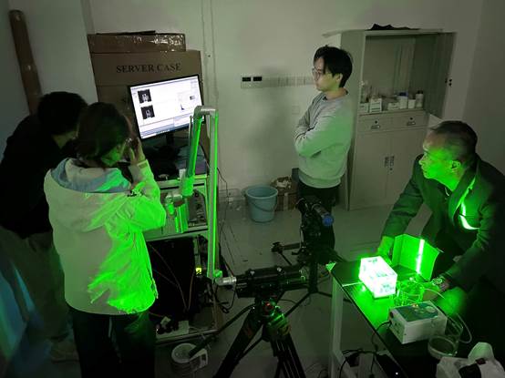A group of people in a room with green lightDescription automatically generated